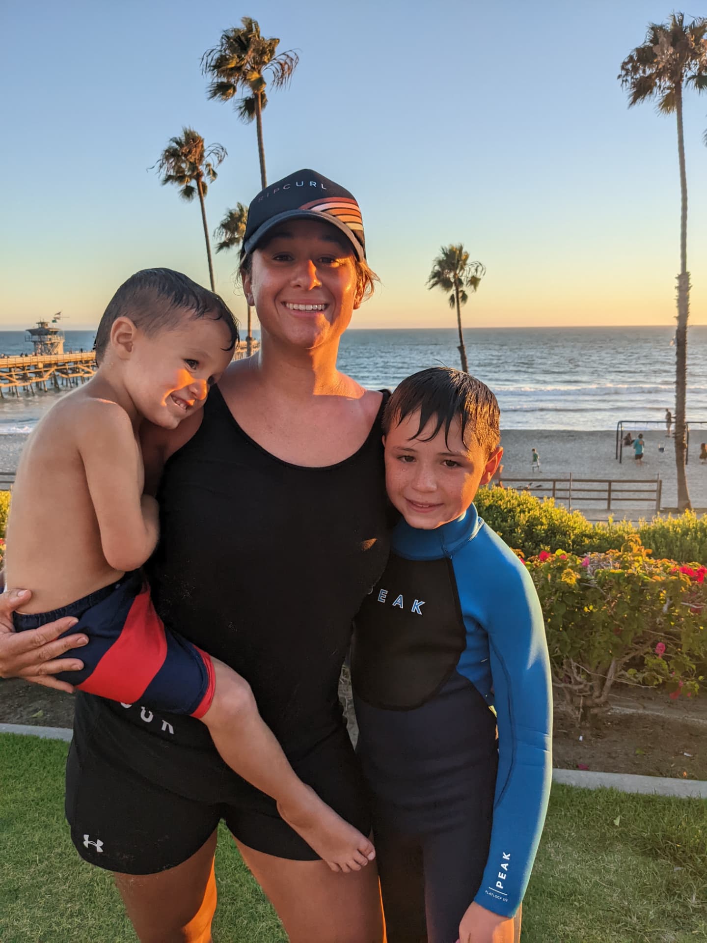 Leah holding two of her boys at the beach during golden hour